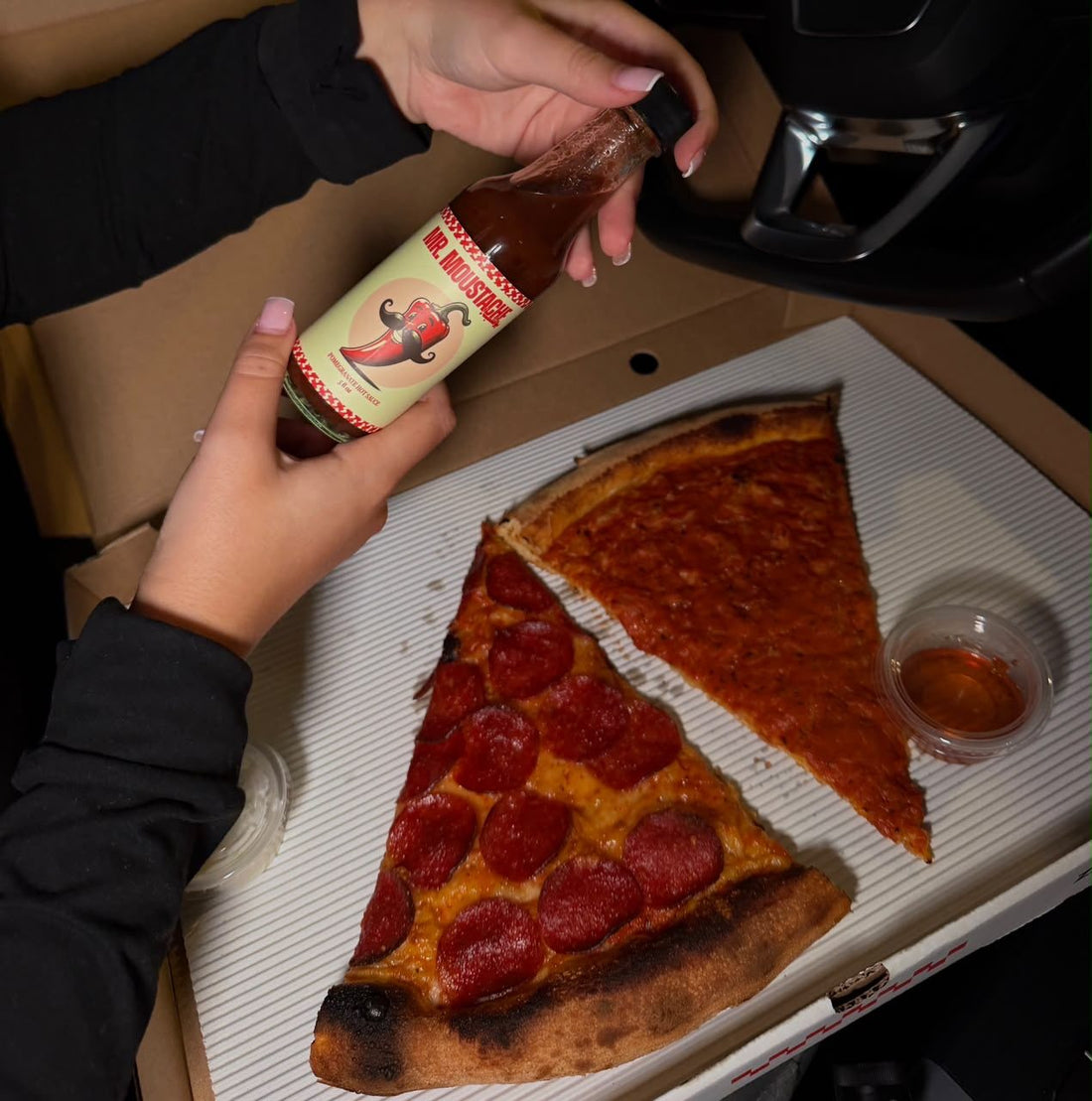 A bottle of Mr. Moustache over two slices of pizza